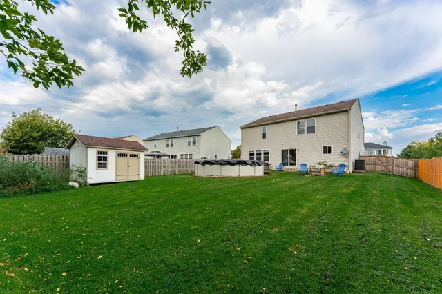 a backyard of a house with plants and large tree