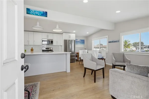 a living room with furniture and a dining table with kitchen appliances