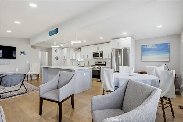 a living room with furniture kitchen view and a wooden floor
