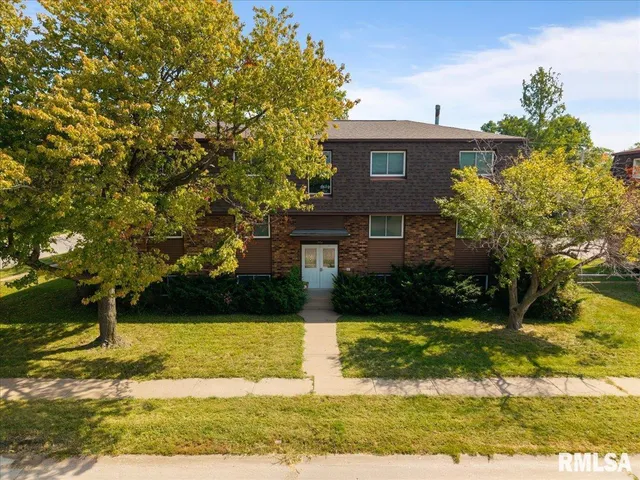 a view of a brick house with a large windows and a yard with plants