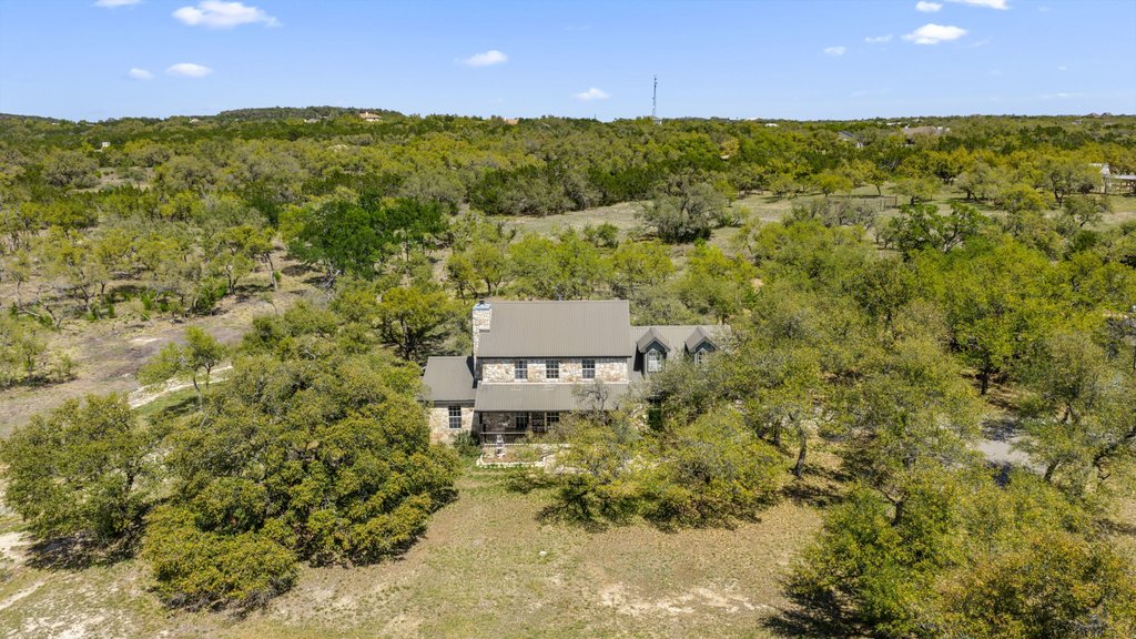 290 Sunset Ridge Dripping Springs, TX 78620 - Photo 35 of 36 Perched atop a verdant hill, this charming stone-clad residence offers a private sanctuary amidst a canopy of mature trees.