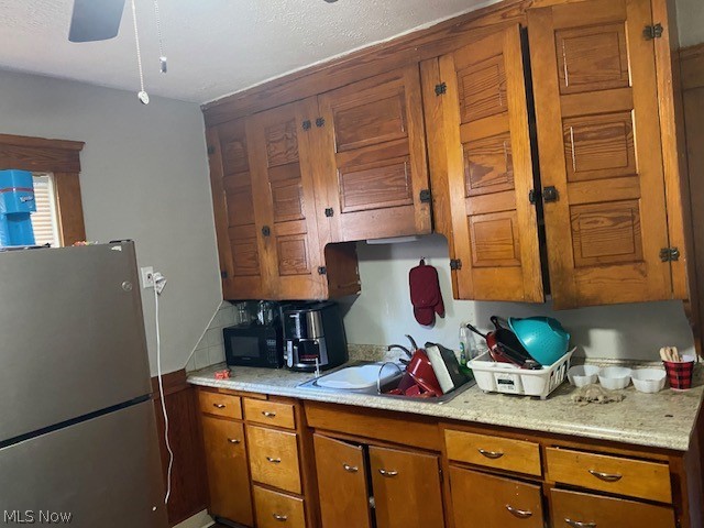 802 Wayside Road Cleveland, OH 44110 - Photo 21 of 33 Kitchen with sink, decorative backsplash, ceiling fan, and stainless steel fridge