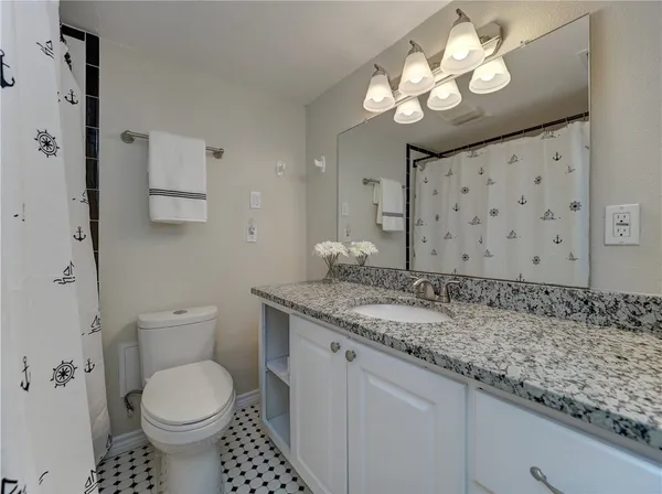 a bathroom with a granite countertop sink a toilet and a large mirror