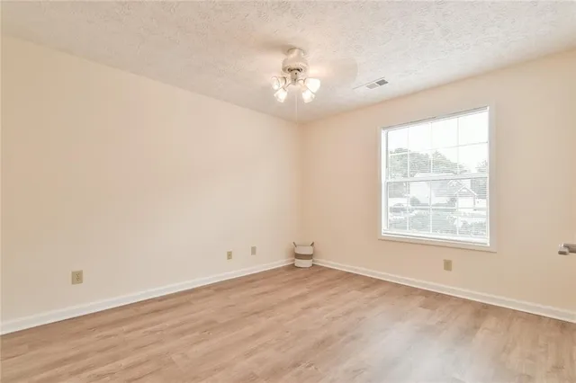 an empty room with wooden floor chandelier and window