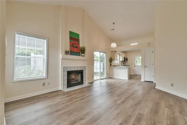 a view of a livingroom with a fireplace a ceiling fan and windows