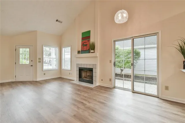 an empty room with wooden floor fireplace and windows