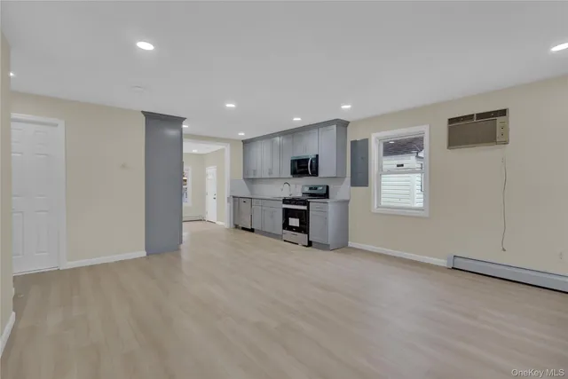 a view of a electric appliances in kitchen and empty room with wooden floor