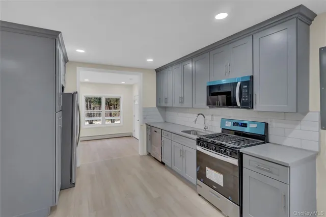 a kitchen with stainless steel appliances a stove a microwave and white cabinets