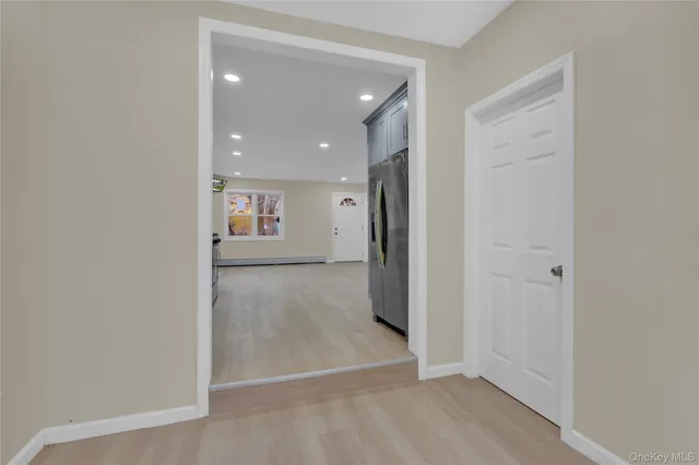 an entryway and an empty room with wooden floor
