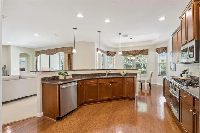 a kitchen with stainless steel appliances granite countertop wooden floors and sink