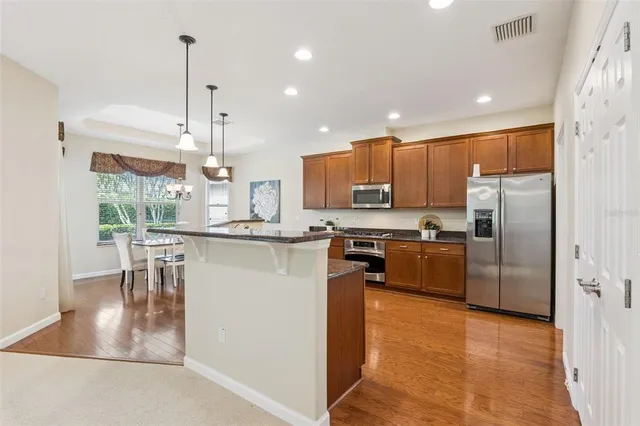 a kitchen with stainless steel appliances granite countertop a refrigerator a oven a sink a dining table and chairs