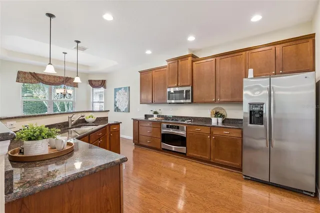 a kitchen with stainless steel appliances granite countertop a sink a stove and a refrigerator