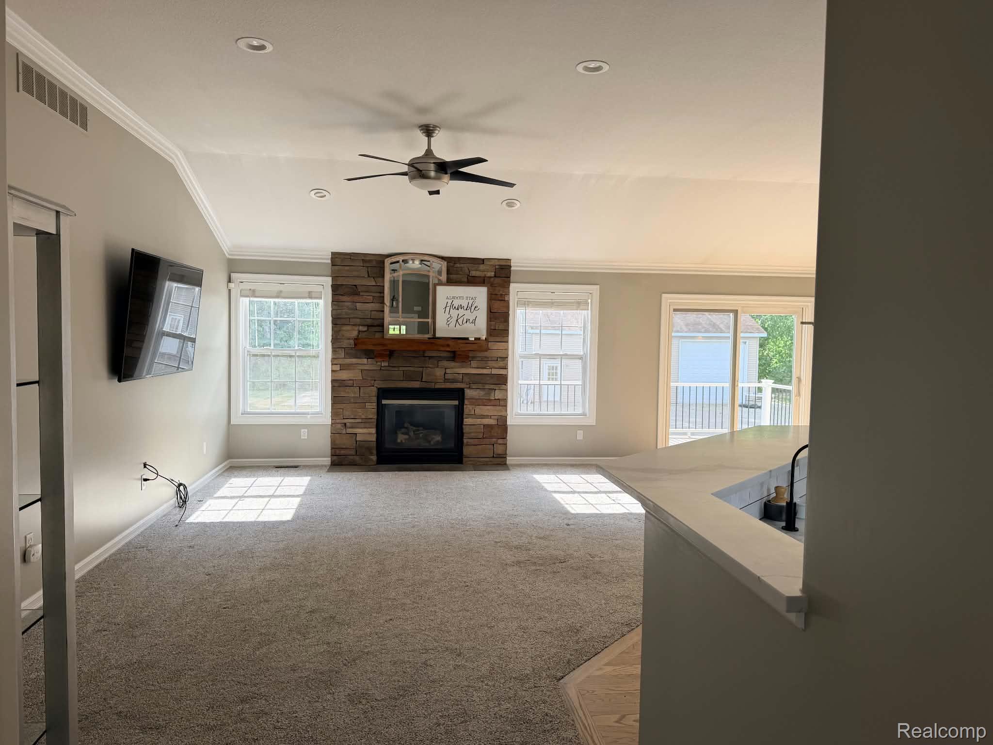 10070 Fenton Road Fenton, MI 48430 - Photo 2 of 21 Stone-accented fireplace with wood mantel, vaulted ceiling with recessed lighting, ceiling fan, and sliding glass door