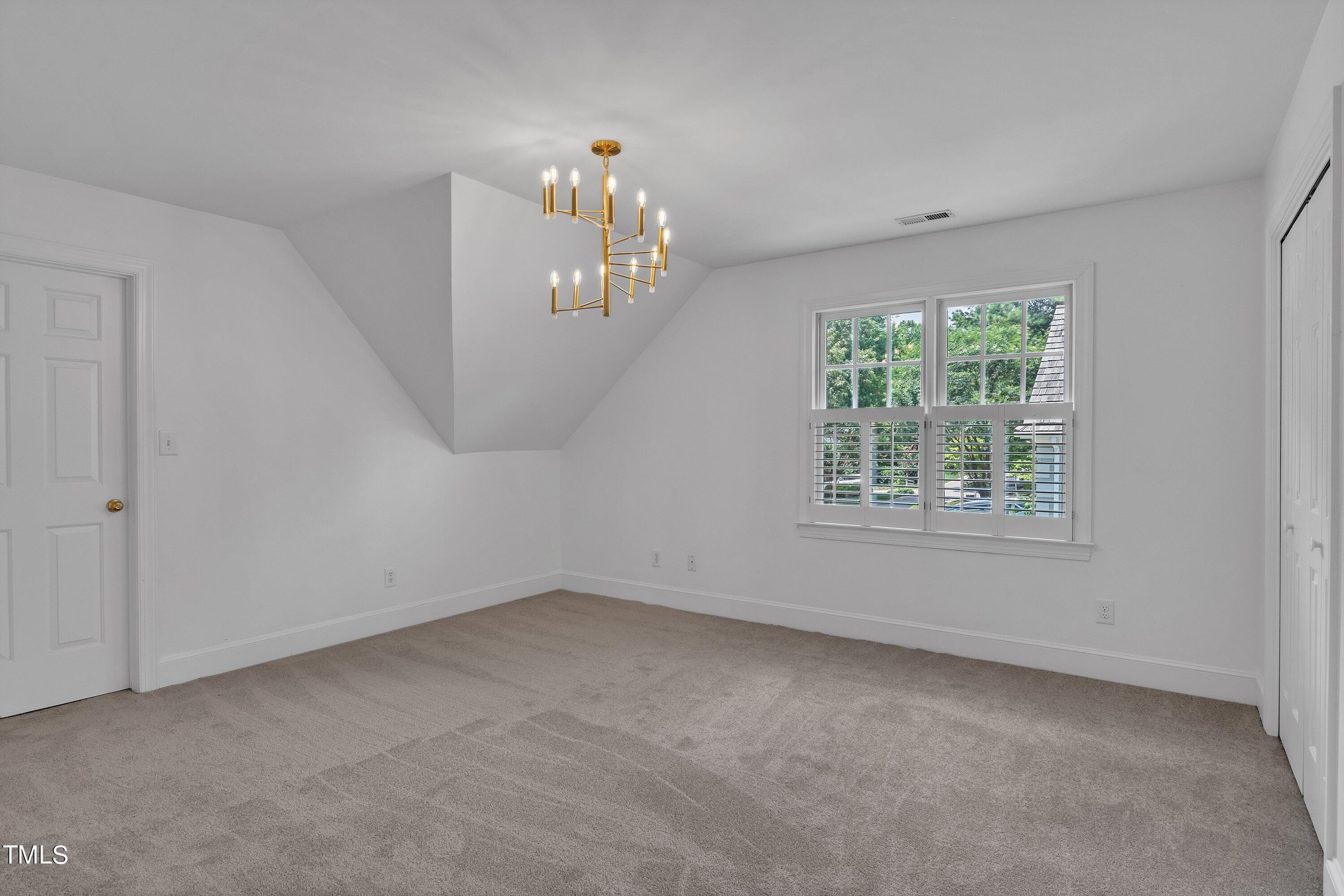 8500 Caldbeck Drive Raleigh, NC 27615 - Photo 30 of 37 an empty room with a chandelier fan and windows