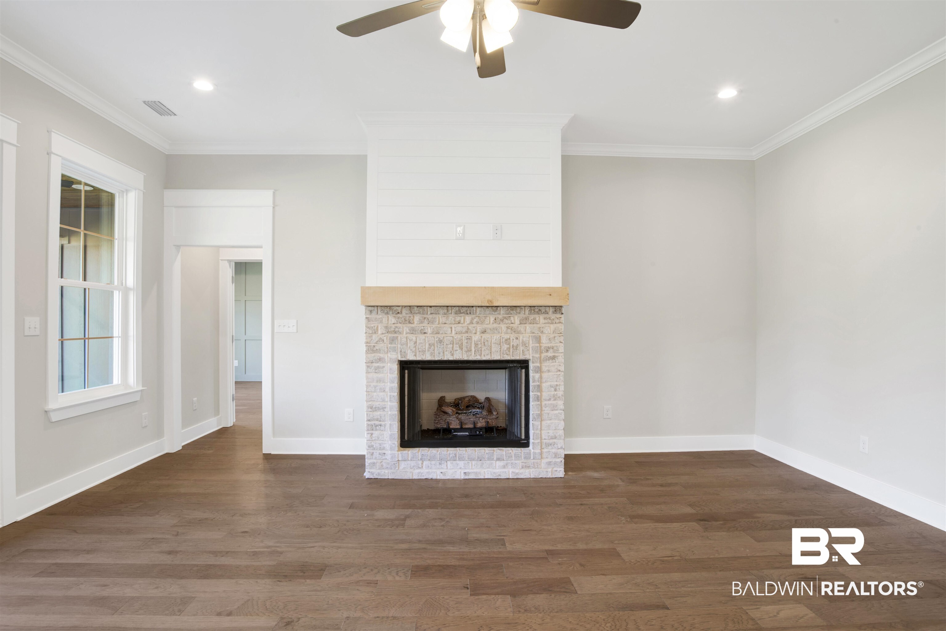 9687 Widgeon Court Daphne, AL 36526 - Photo 8 of 40 Unfurnished living room featuring a brick fireplace, ceiling fan, dark hardwood / wood-style flooring, and ornamental molding