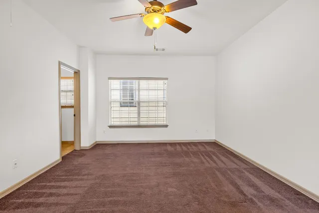 an empty room with a window and a ceiling fan