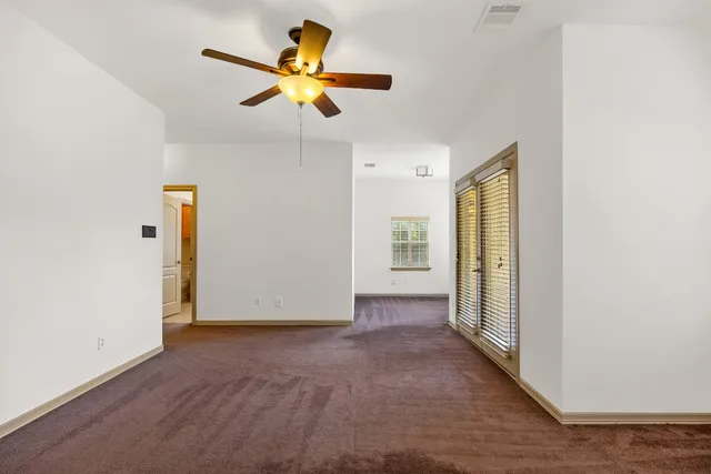 an empty room to ceiling window and ceiling fan