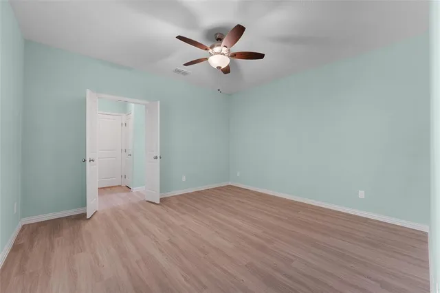 an empty room with wooden floor a ceiling fan and stairs