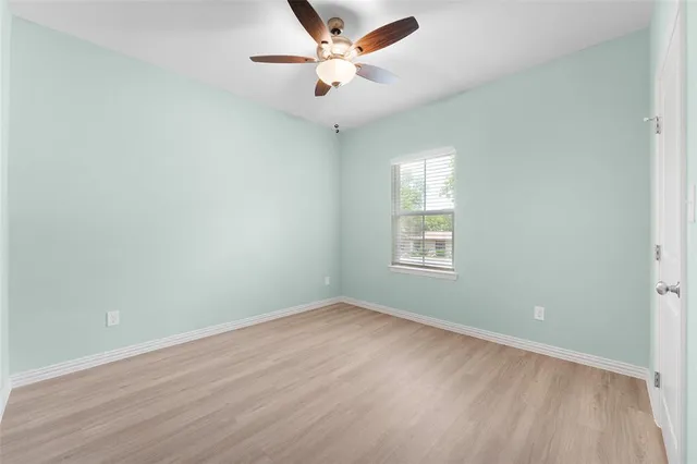 an empty room with a window and a ceiling fan