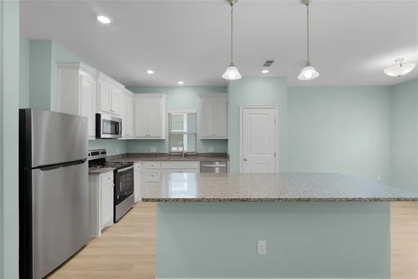 a kitchen with stainless steel appliances granite countertop a refrigerator a sink a stove and a sink