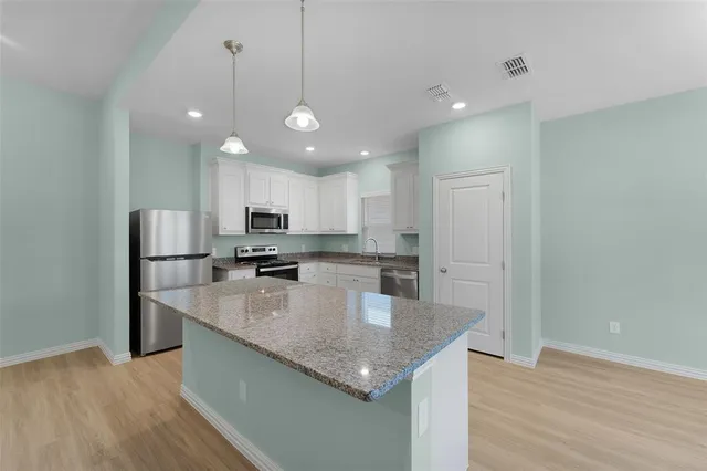 a kitchen with stainless steel appliances granite countertop a sink a stove and a refrigerator