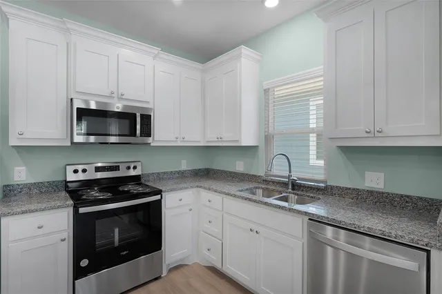 a kitchen with granite countertop white cabinets and stainless steel appliances
