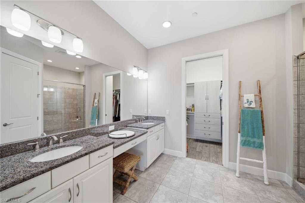 9658 Montelanico Loop, Unit 201 Naples, FL 34119 - Photo 17 of 46 a bathroom with a granite countertop double vanity sink mirror and shower