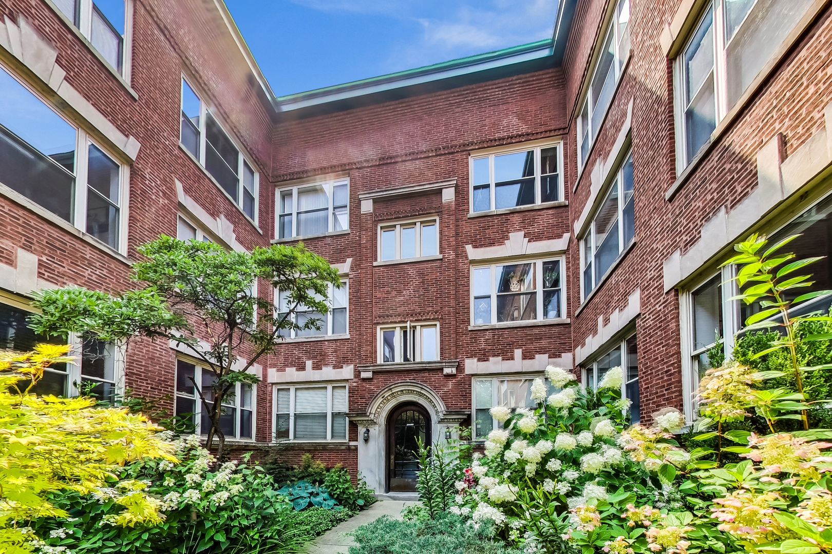 4638 North Racine Avenue, Unit 1 Chicago, IL 60640 - Photo 23 of 26 a front view of a multi story residential apartment building with a yard