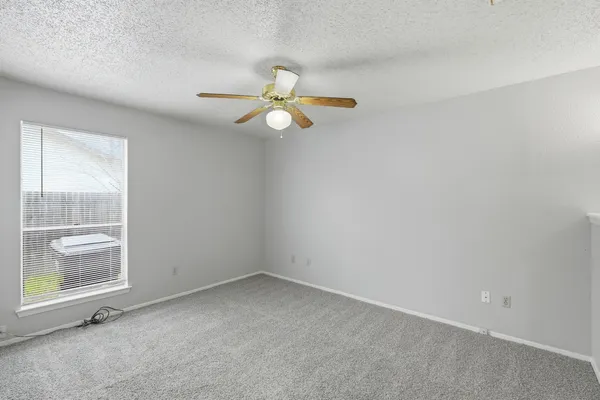 an empty room with a window and a fan