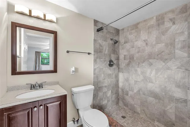 a bathroom with a granite countertop sink toilet a mirror a vanity and shower