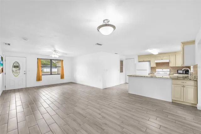 a view of an empty room with window and wooden floor