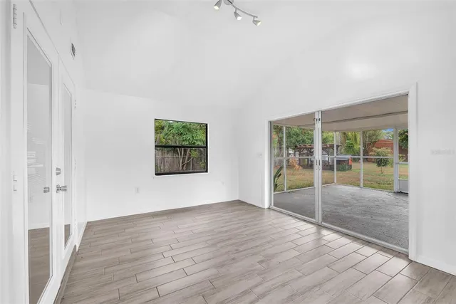 an empty room with wooden floor and windows