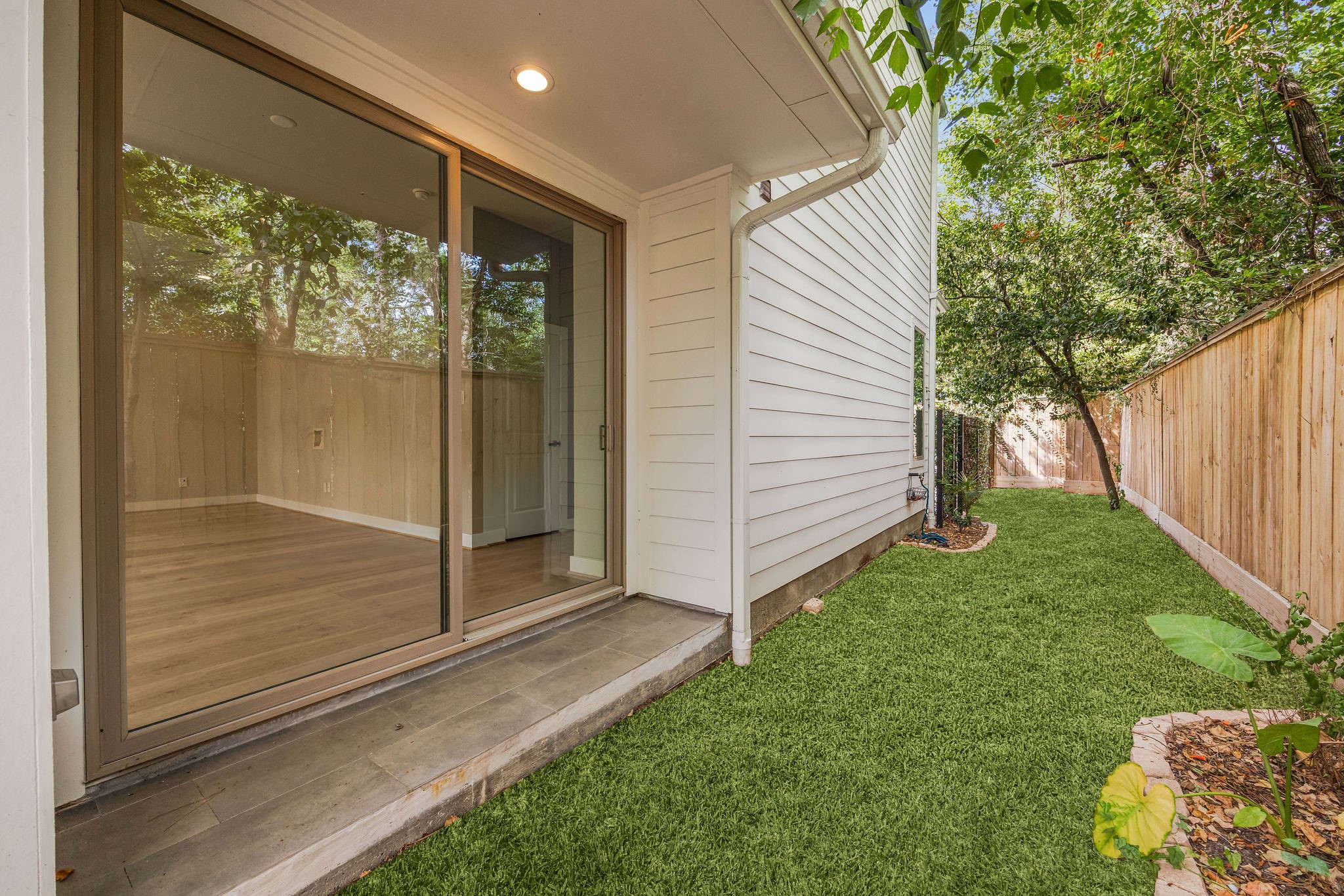 540 Janisch Road, Unit A Houston, TX 77018 - Photo 3 of 18 Private fenced backyard with a covered patio, low-maintenance green space, and large sliding glass doors connecting the outdoors to the main living area.