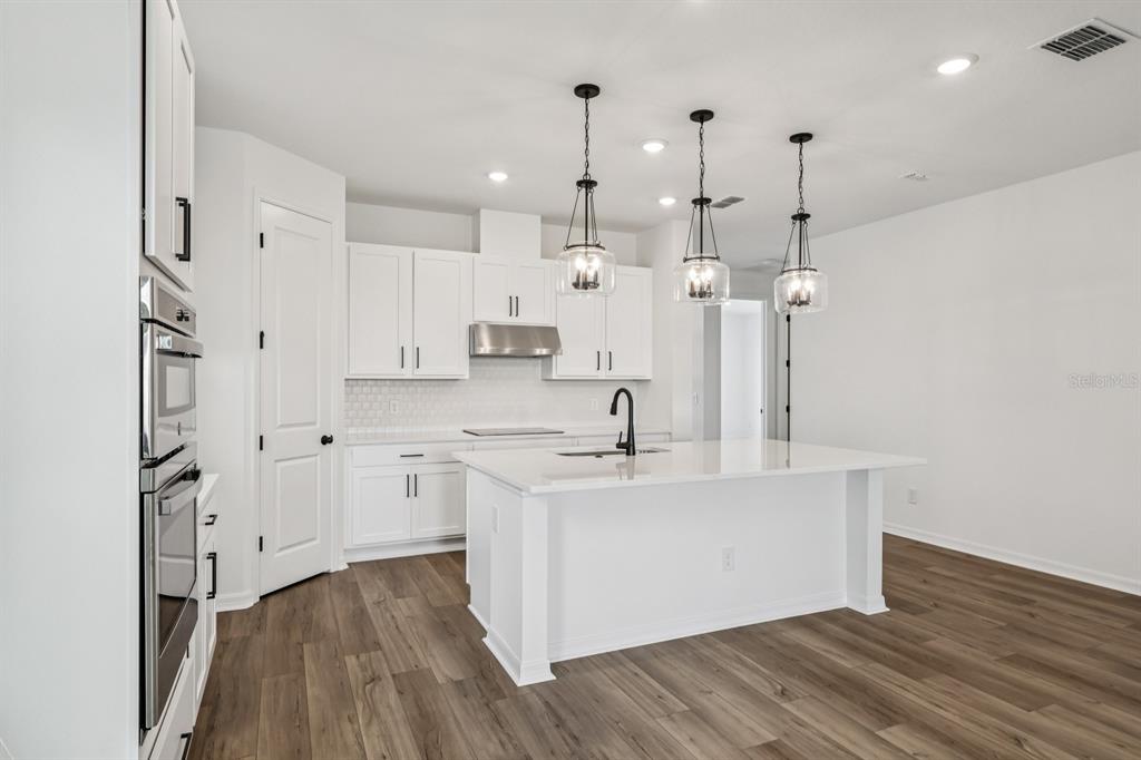 6644 Wake Street St. Cloud, FL 34771 - Photo 12 of 48 a large kitchen with stainless steel appliances a large counter top a stove a sink and a chandelier