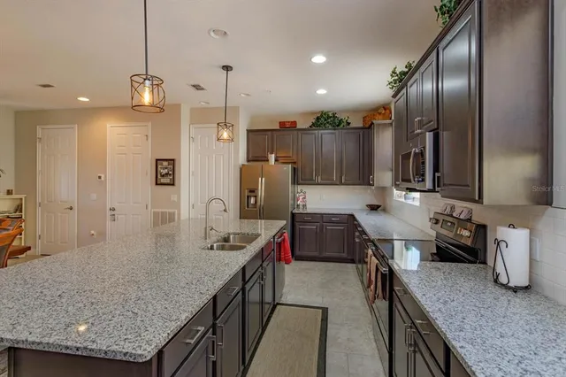 a kitchen with stainless steel appliances granite countertop sink stove refrigerator and cabinets