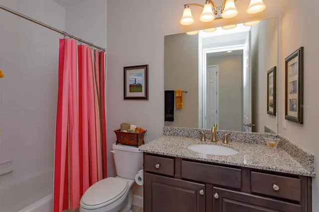 a bathroom with a granite countertop sink vanity mirror and toilet