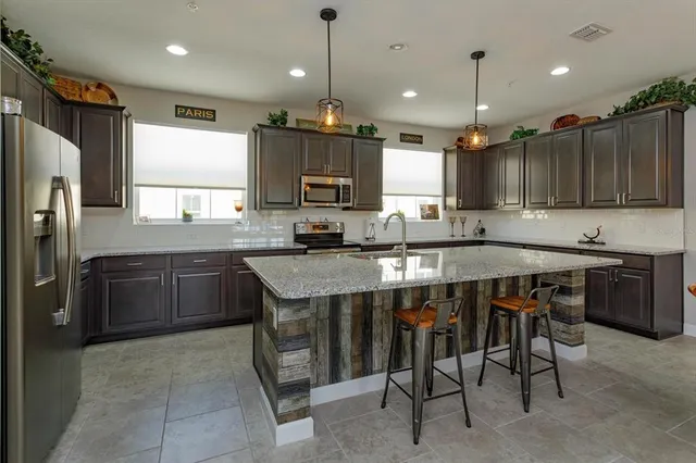 a kitchen with kitchen island granite countertop a table chairs microwave and refrigerator