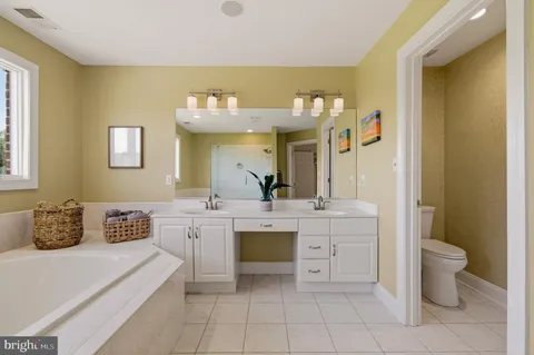 a spacious bathroom with a double vanity sink a mirror and a bathtub