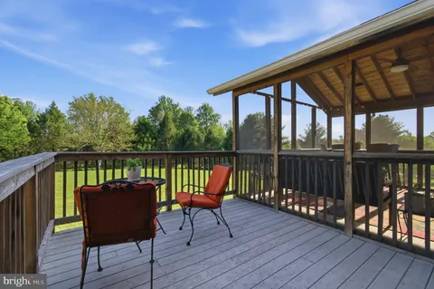 a balcony with wooden floor outdoor seating and yard in the back