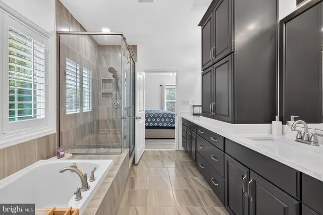 a spacious bathroom with a granite countertop tub sink a mirror a shower and vanity