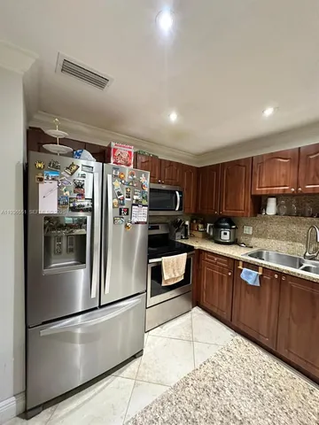 a kitchen with stainless steel appliances granite countertop a refrigerator and a sink