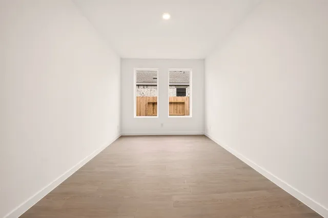 a large white kitchen with stainless steel appliances kitchen island large trees and wooden floors