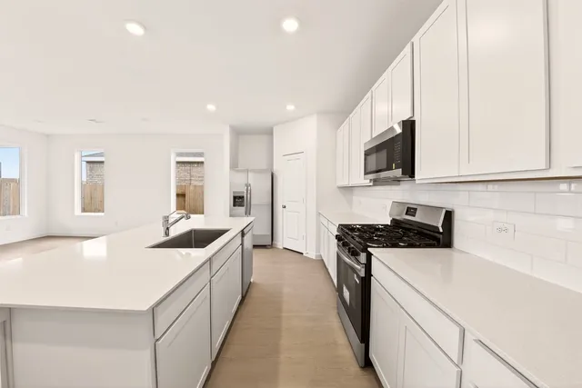 a kitchen with kitchen island a sink a stove a refrigerator and white cabinets