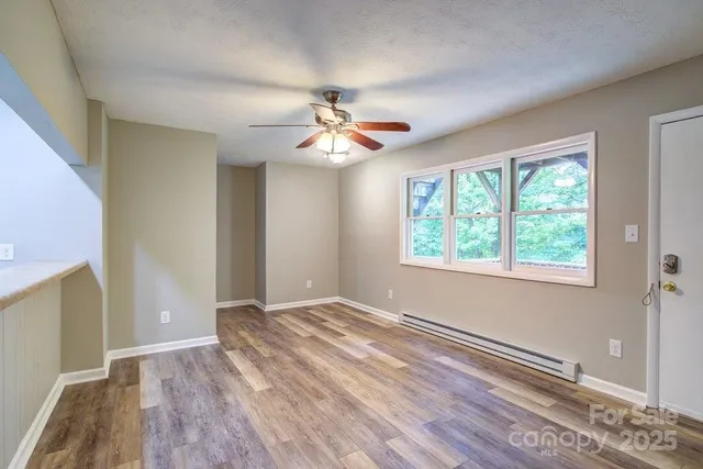 a view of an empty room with a window and wooden floor