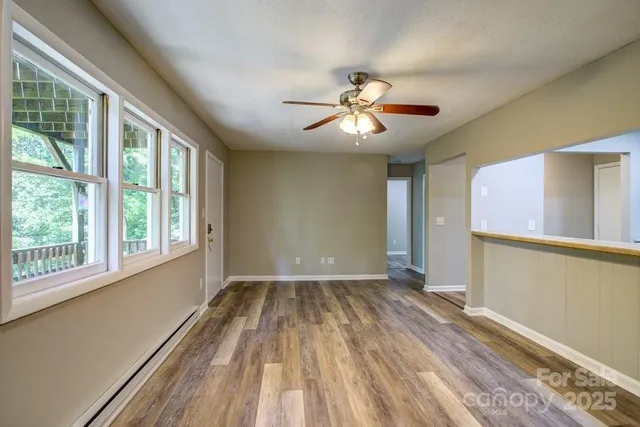 a view of empty room with wooden floor and fan