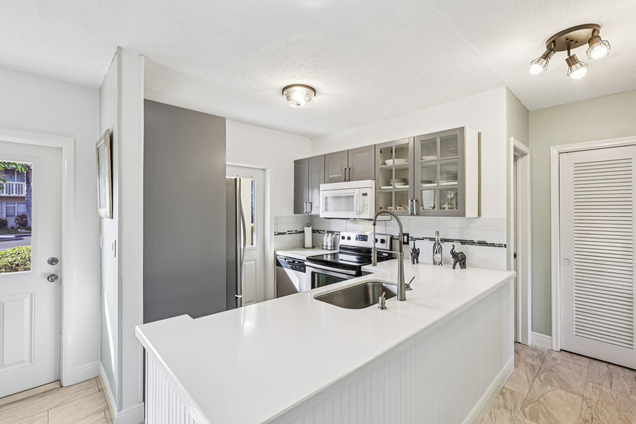 2131 Northeast 42nd Court, Unit 106E Lighthouse Point, FL 33064 - Photo 12 of 33 a kitchen with kitchen island a sink appliances and cabinets