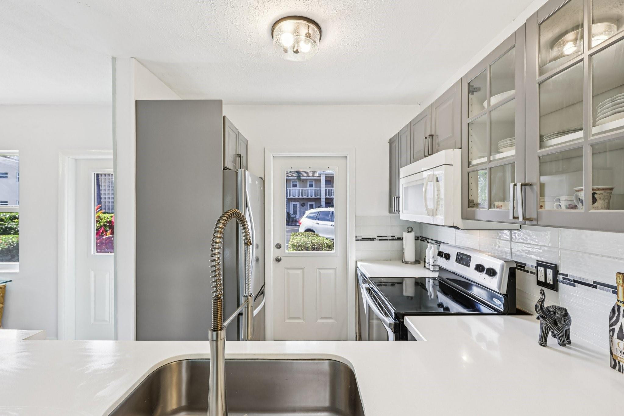 2131 Northeast 42nd Court, Unit 106E Lighthouse Point, FL 33064 - Photo 13 of 33 a kitchen with stainless steel appliances granite countertop a sink and a refrigerator