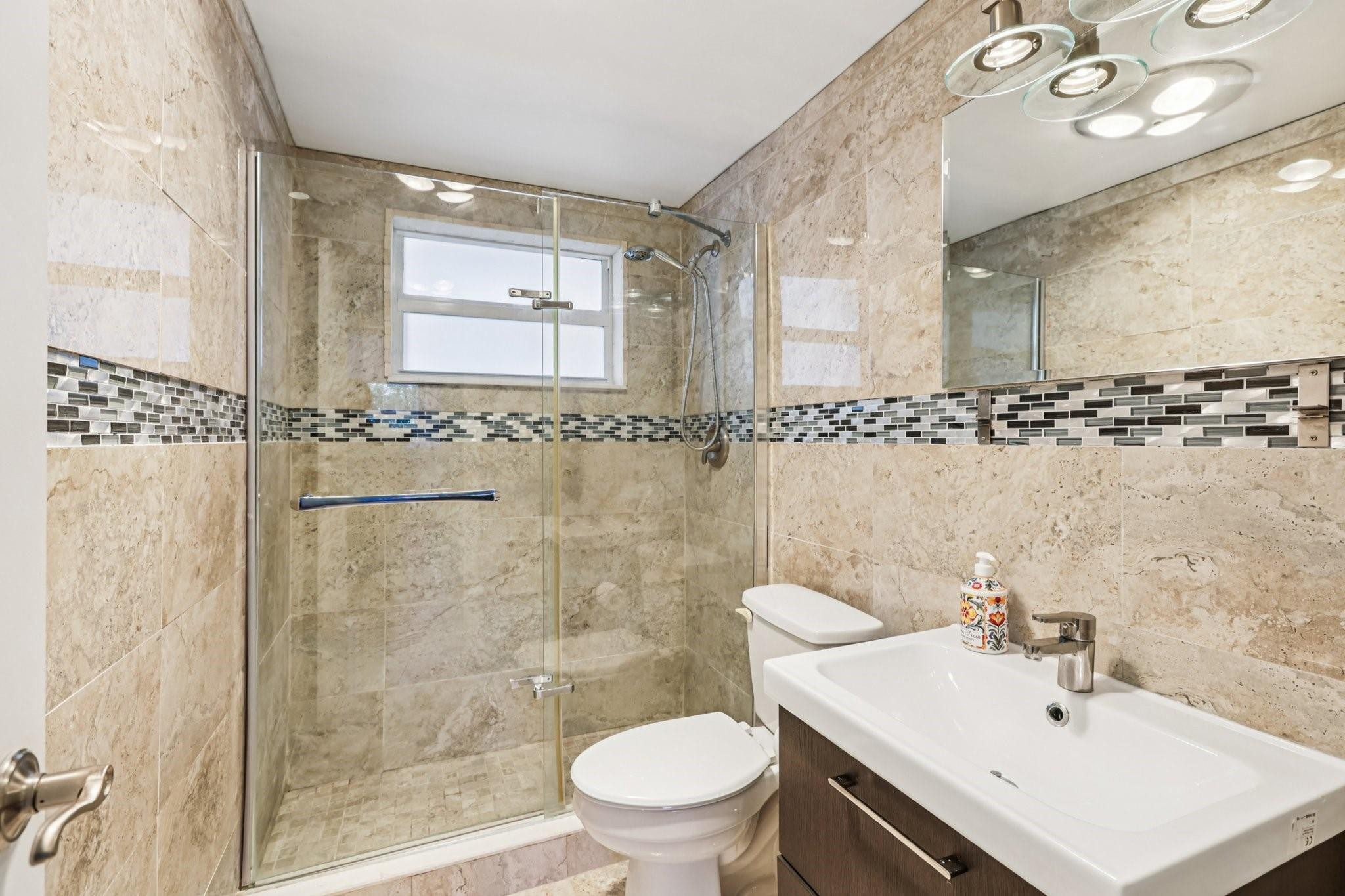 2131 Northeast 42nd Court, Unit 106E Lighthouse Point, FL 33064 - Photo 20 of 33 a bathroom with a sink mirror toilet and shower