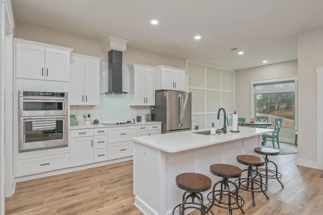a kitchen with stainless steel appliances kitchen island granite countertop a stove a sink a dining table and chairs
