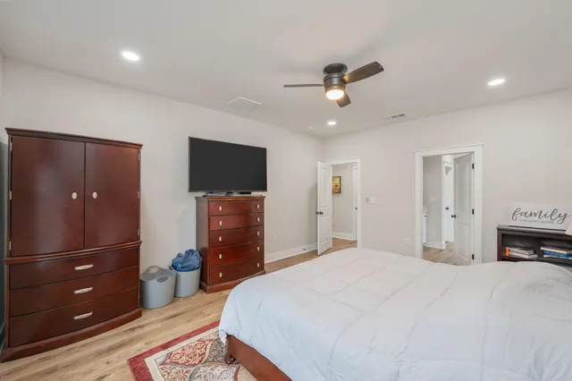 a bedroom with a bed a mirror on dresser and a chandelier